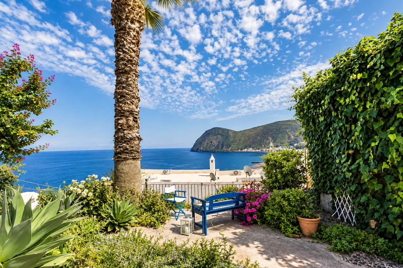 Il giardino con la palma e la panca blu affacciati sulla baia di Canneto