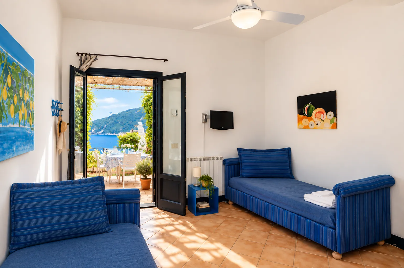 Il soggiorno con due letti singoli blu aperto sulla terrazza
