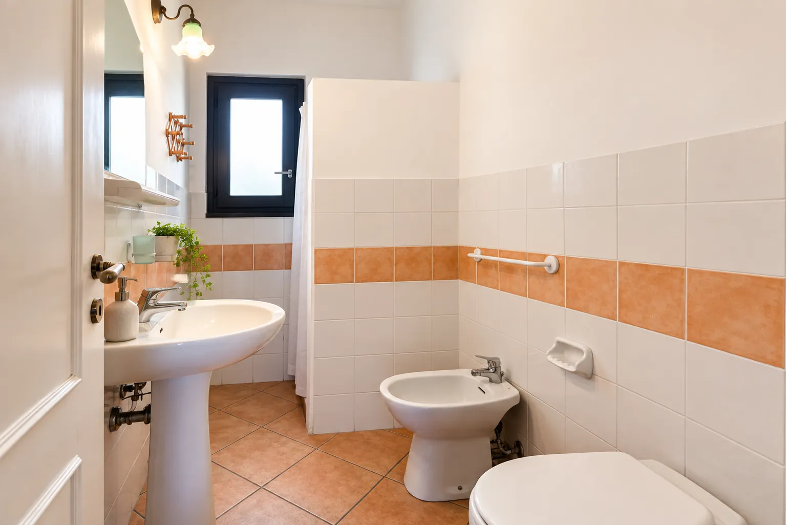 Il bagno con maioliche bianche e fascia terracotta