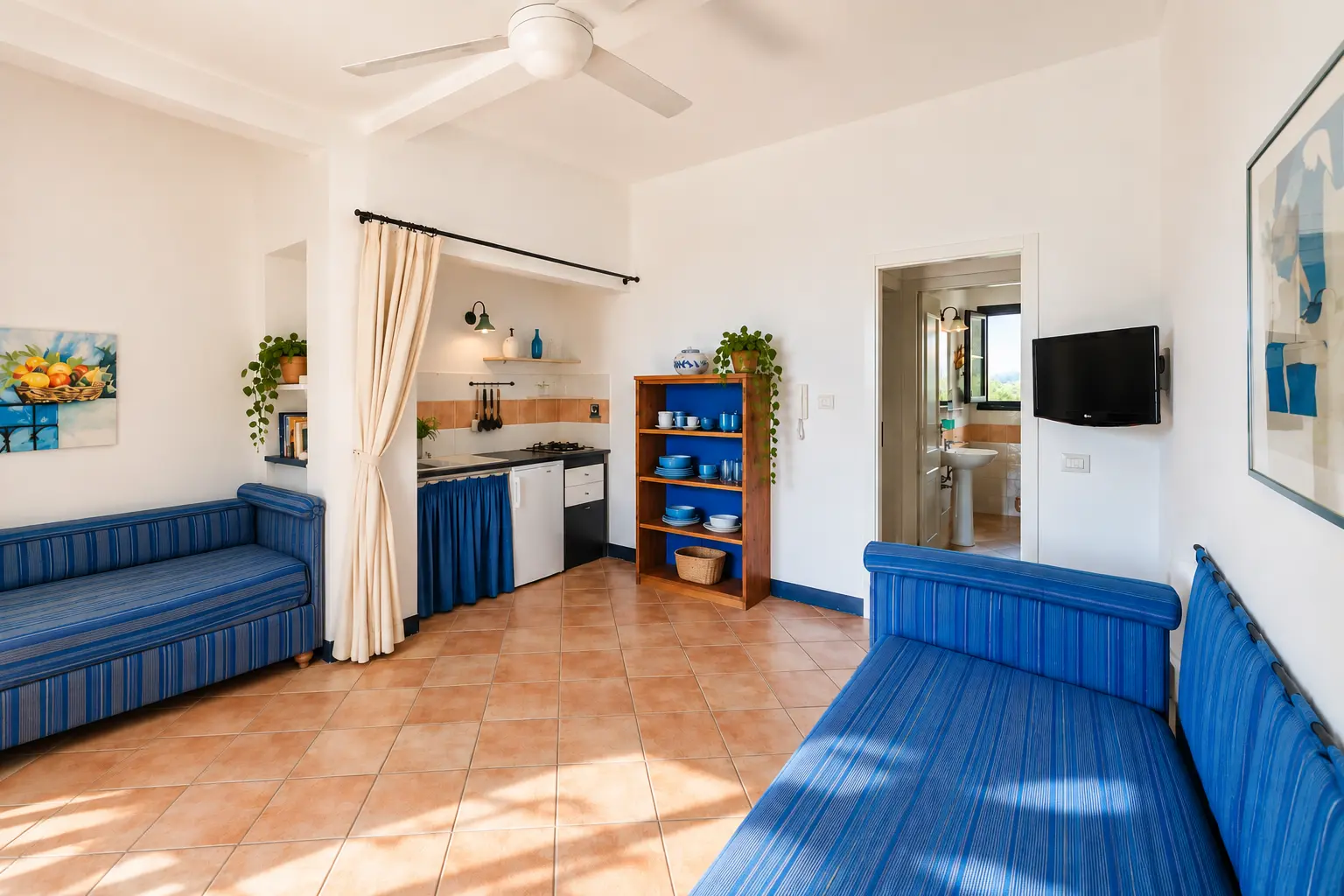 La zona giorno con i due divani letto blu e l’angolo cucina