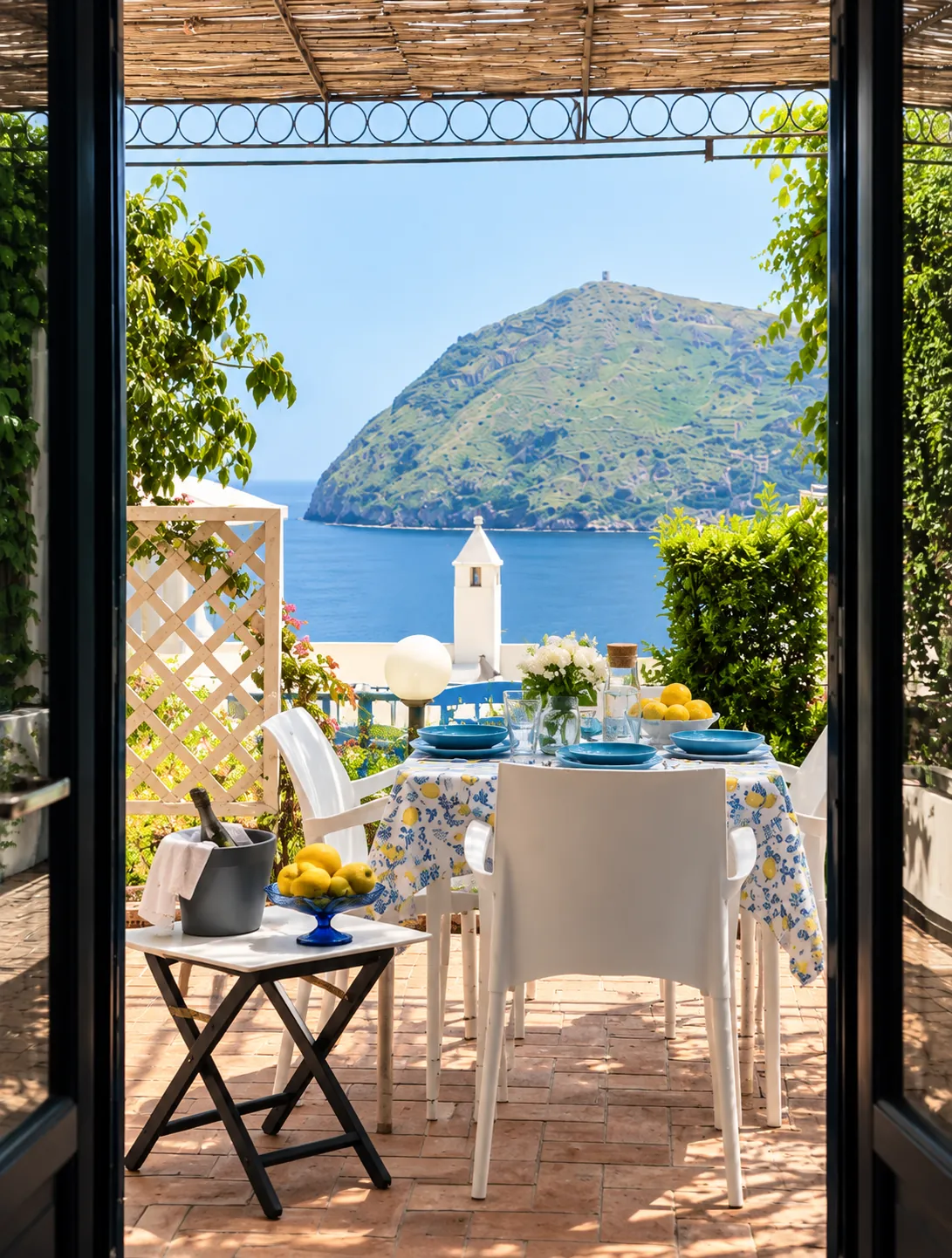 La tavola in terrazza vista dalla portafinestra, con la baia di Canneto