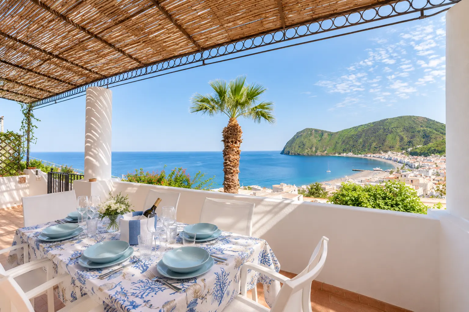 La grande terrazza coperta con la tavola apparecchiata e la baia di Canneto