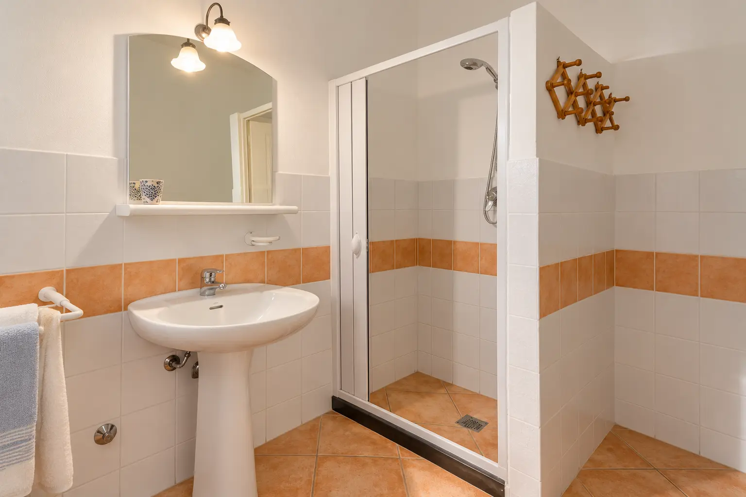 Il bagno con maioliche bianche e fascia terracotta