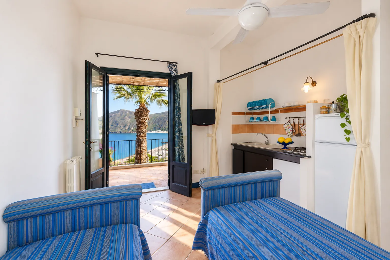 La zona giorno con due letti singoli blu e la porta aperta sul mare