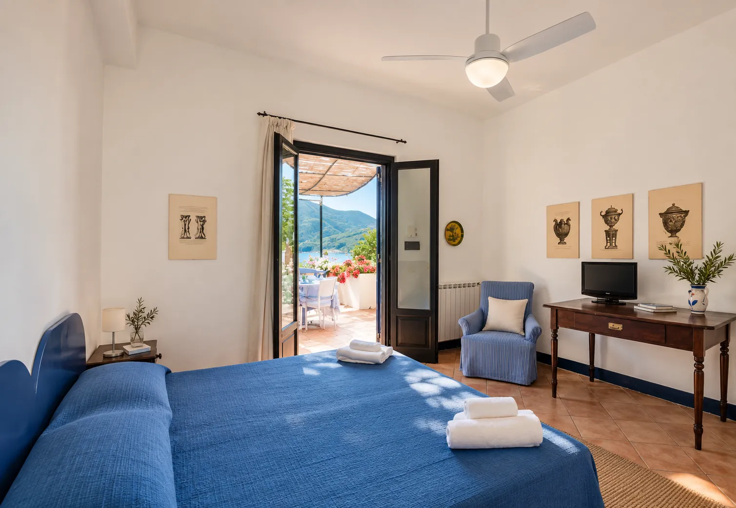 La camera con letto blu e la porta aperta sulla terrazza fiorita