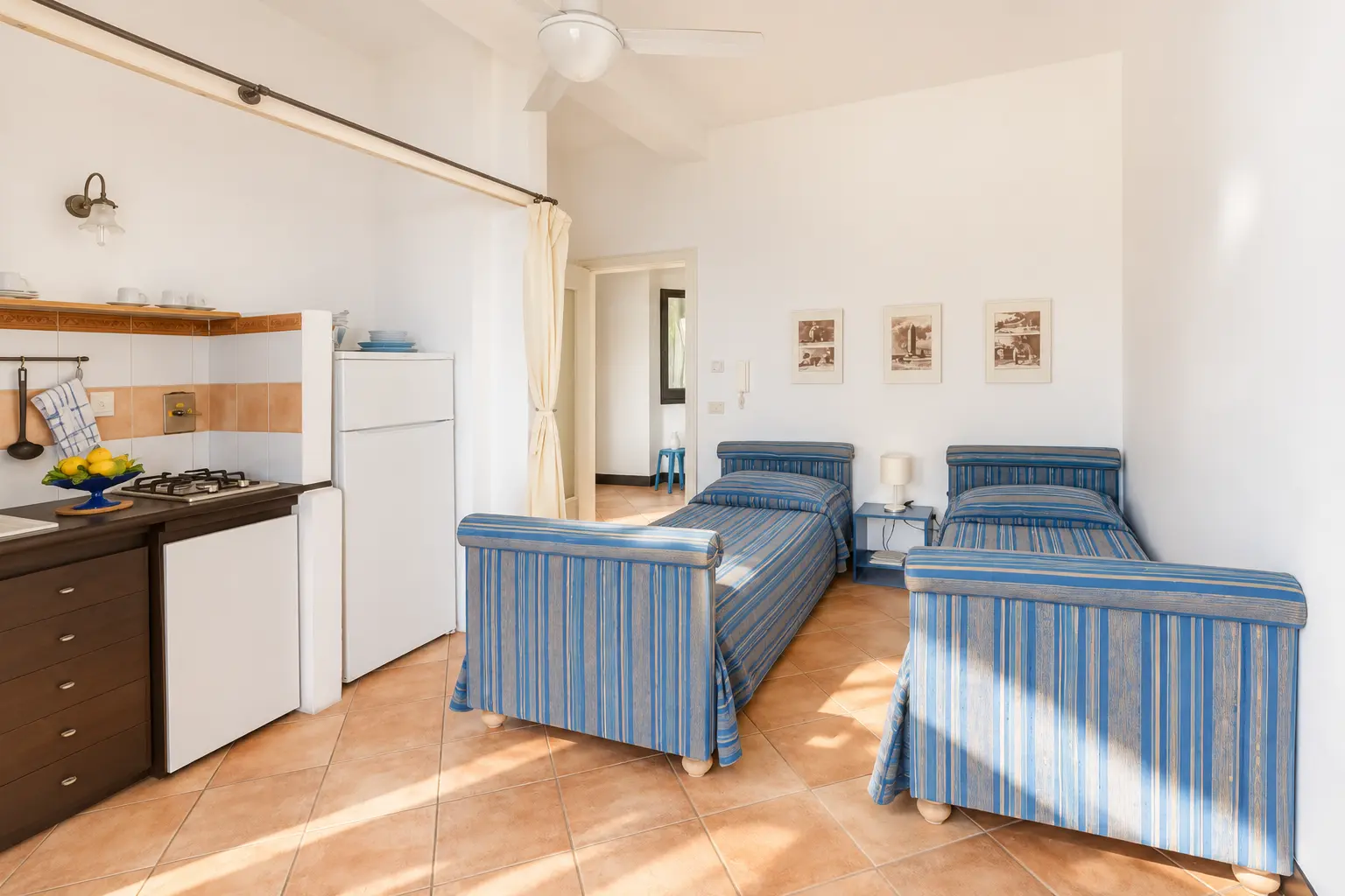 La zona giorno con cucina e due letti singoli blu