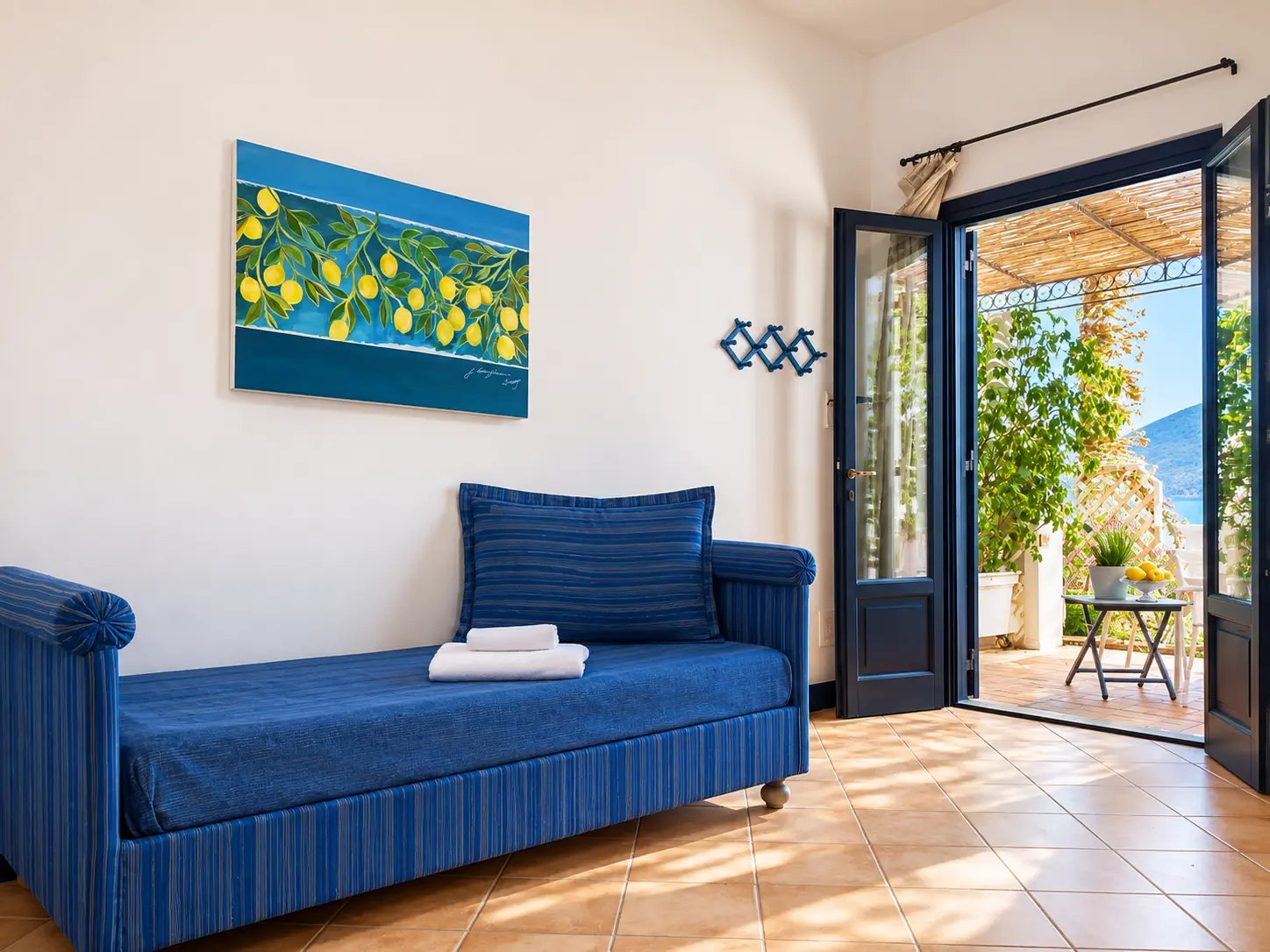 La stanza giorno con il divano blu e la porta aperta verso la terrazza